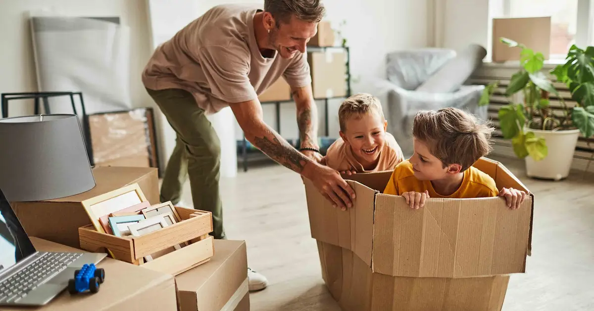 Father and kids play in a cardboard box during a fun move.