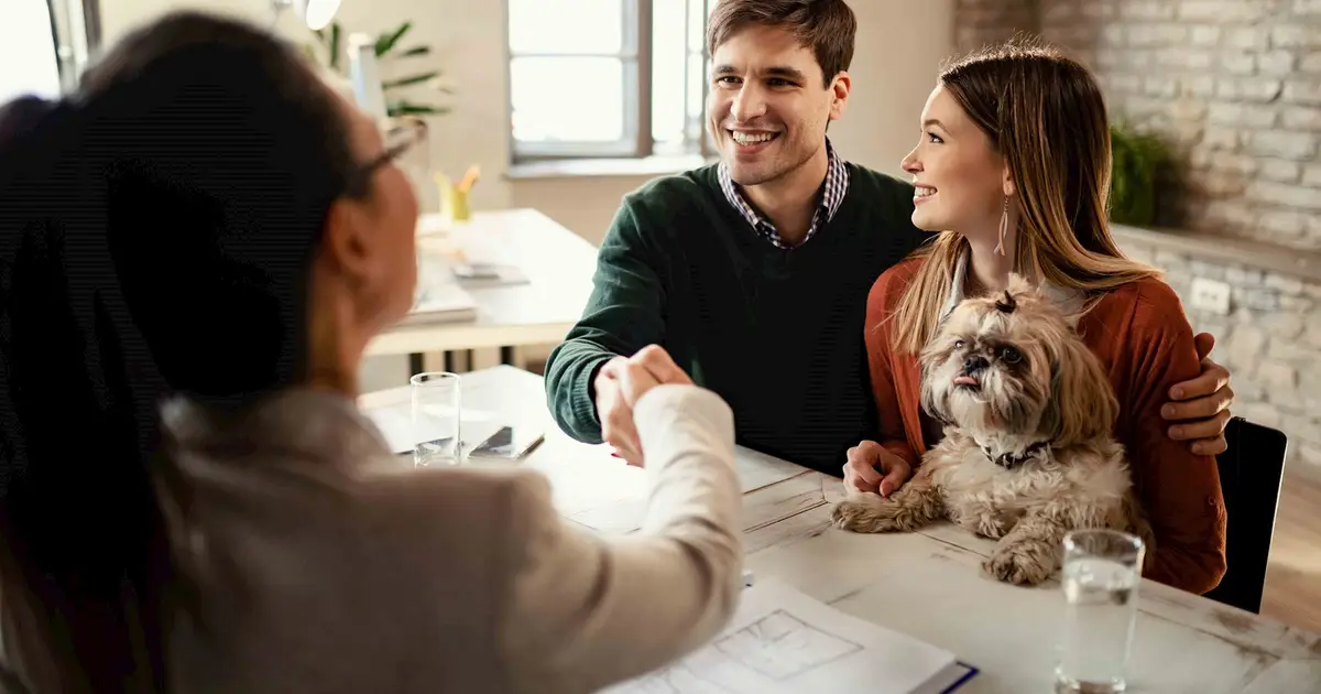 Couple shaking hands with agent during consultation.